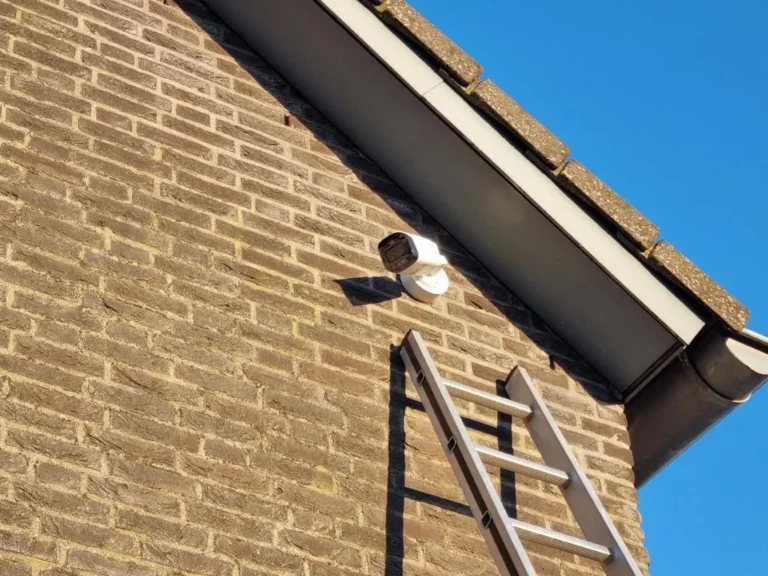 Monteur bevestigt een camera onder de dakgoot van een woning