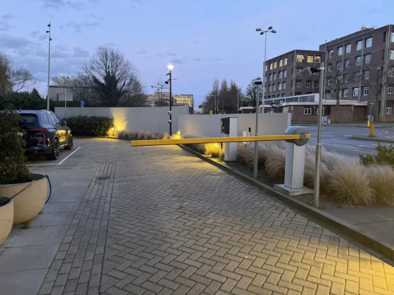 Parkeerterrein met slagboom en camerabewaking in de schemering