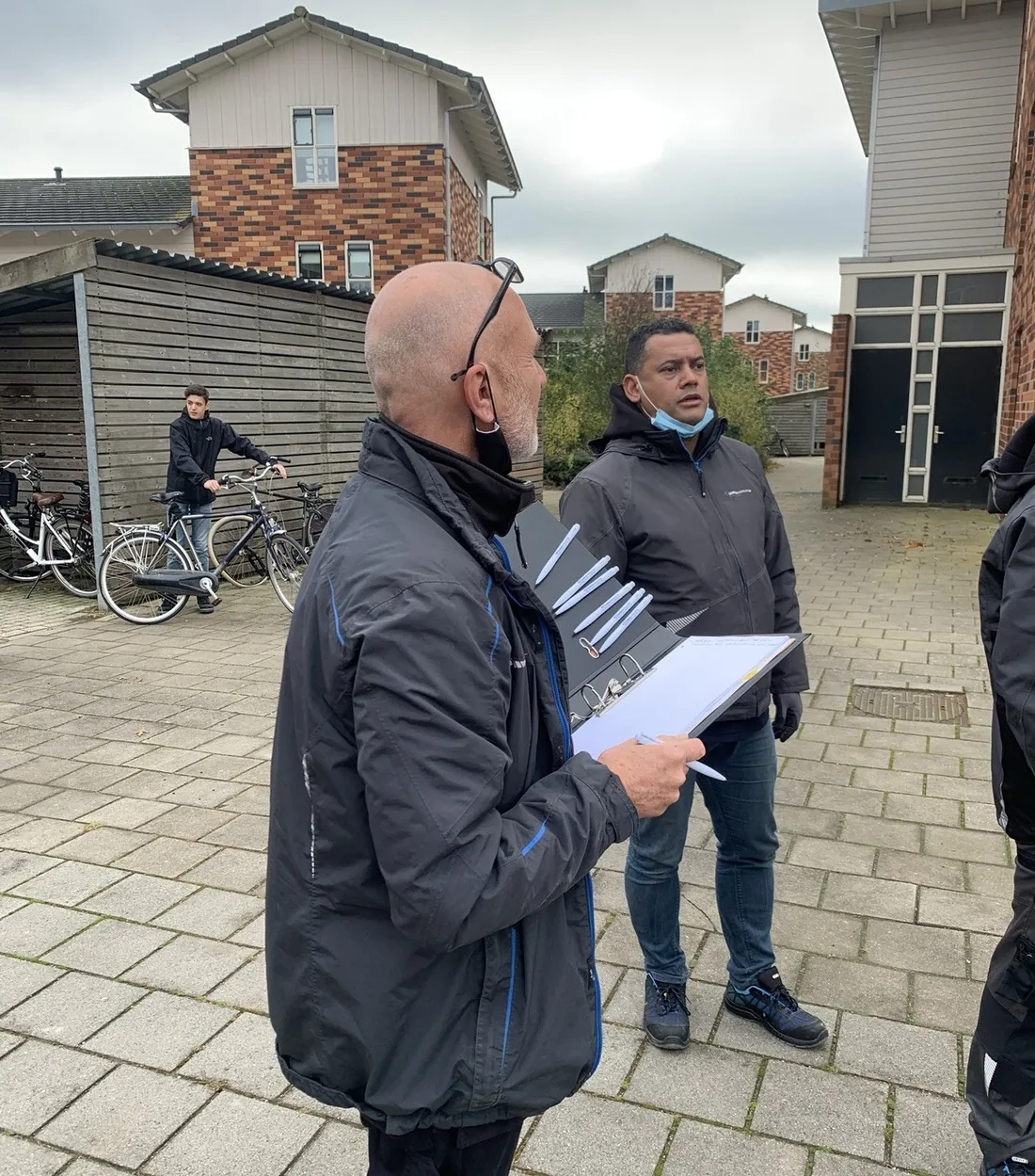 Twee mensen lopen het terrein af met de tekening erbij