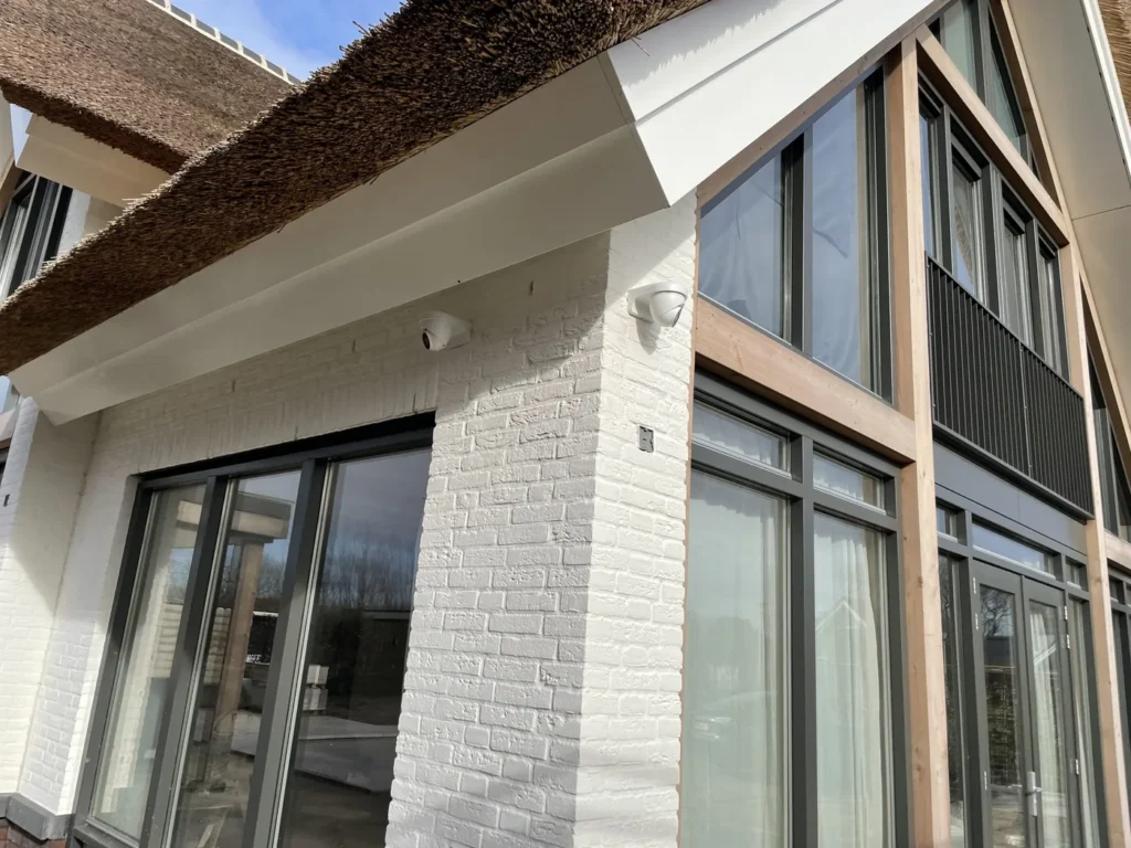 Twee dome-camera's strak weggewerkt onder de rietkap van een villa