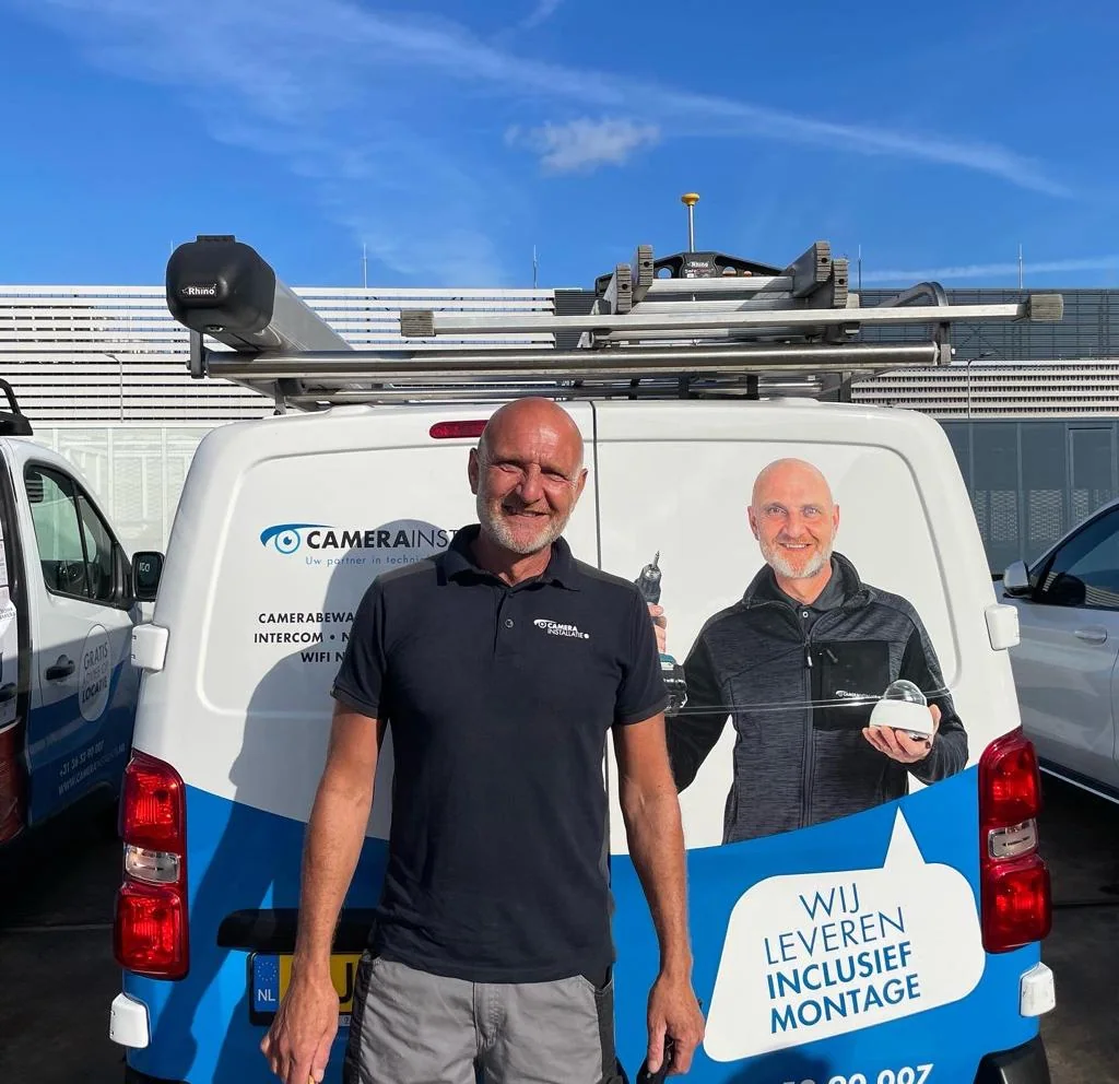 Monteur van CameraInstallatie.nl bij zijn bus, met zijn eigen portret op de zijkant